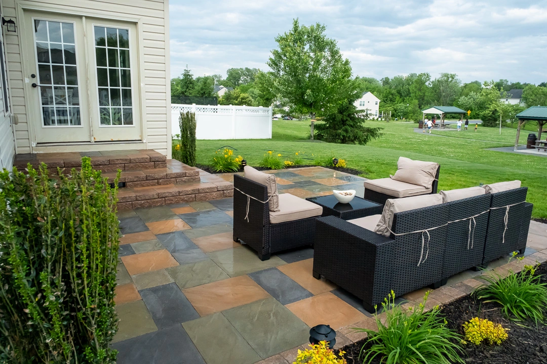 Outdoor patio with a table and chairs, situated in front of a house, designed by professional landscaper Hawkins Landscaping.