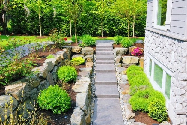 Beautiful front yard landscaping with rocks and greenery by Hawkins Landscaping, featuring stone steps, lush shrubs, and natural rock borders.