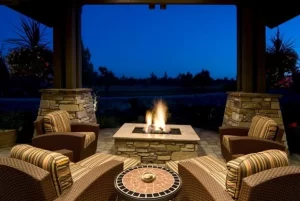 Beautiful outdoor patio with a stone fire pit surrounded by cozy chairs, showcasing elegant landscaping and hardscaping design by Hawkins Landscaping.