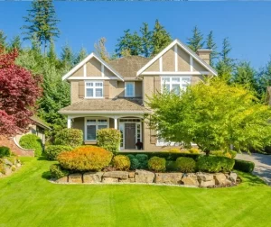 Beautiful front yard featuring landscaping with rocks, green lawn, and colorful fall shrubs in front of a modern suburban home.