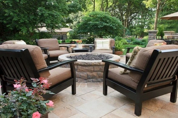 Inviting backyard patio with cushioned chairs surrounding a stone fire pit, featuring beautifully crafted landscaping and hardscaping by Hawkins Landscaping.