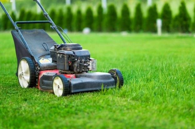 Professional lawn maintenance with a push mower on a lush green yard by Hawkins Landscaping.