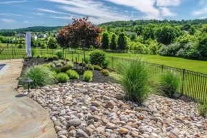 Landscaping with rock ideas featuring mixed plants and river rocks by Hawkins Landscaping.