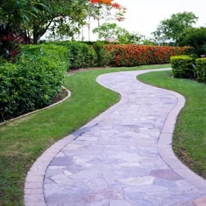 Curved stone walkway ideas bordered by lush green lawn and manicured shrubs, designed and installed by Hawkins Landscaping.