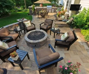 A stylish backyard patio with a circular fire pit, comfortable seating, and stone pavers, showcasing inviting patio ideas designed by Hawkins Landscaping.