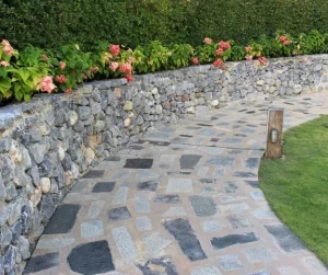 Creative landscaping ideas featuring a curved stone walkway, natural rock retaining wall, and flowering plants, designed by Hawkins Landscaping.