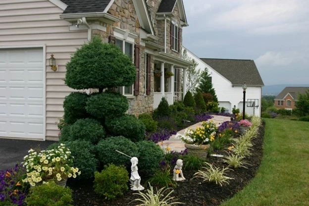 Landscape design showcasing a professionally designed front yard with manicured shrubs, colorful flower beds, and clean mulch lines by Hawkins Landscaping.
