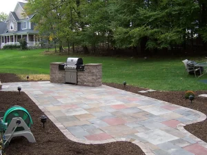 Custom patio with paver surface, built-in grill station, and clean garden edging highlighting professional hardscapes landscaping by Hawkins Landscaping.