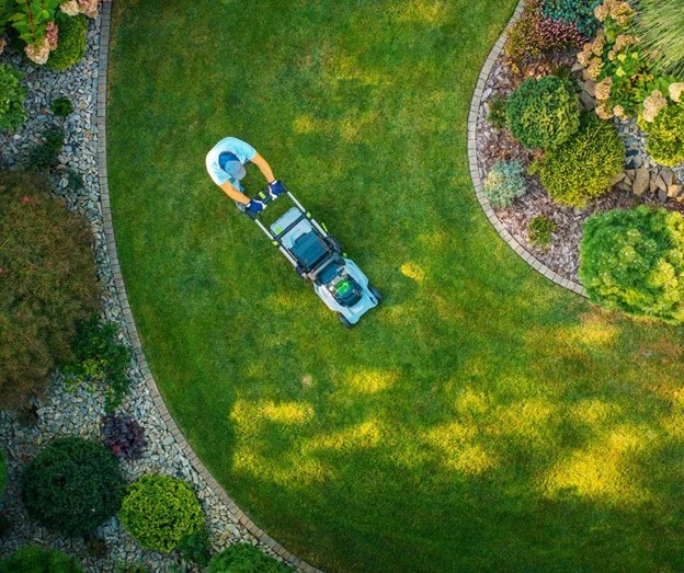 Aerial view of a homeowner mowing a neatly edged lawn, showing professional lawn care and maintenance by Hawkins Landscaping.