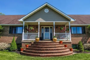 Front home entrance featuring brick steps, manicured lawn, and vibrant garden beds showcasing hardscapes and landscapes by Hawkins Landscaping.