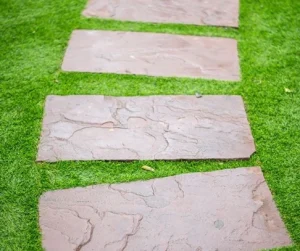 Straight garden path featuring walkways with stepping stones set in green grass by Hawkins Landscaping.