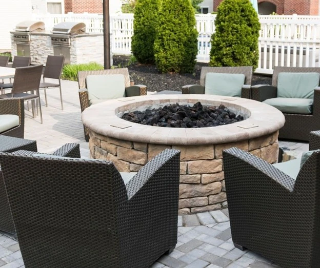 A stylish patio with fire pit by Hawkins Landscaping, featuring comfortable seating and a stone fire pit, perfect for outdoor gatherings.