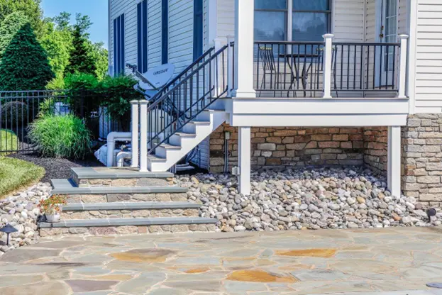 Stone steps, patio surface, and decorative rock base showcasing what are hardscapes in a modern home landscape by Hawkins Landscaping.