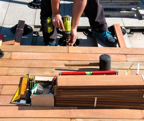 Deck installation by Hawkins Landscaping showing a professional installing premium wood decking with precision tools for a clean and durable outdoor living space.