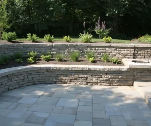 Hardscapes and masonry project by Hawkins Landscaping featuring a paver patio, tiered retaining walls, built-in seating, and professionally landscaped garden beds for an elegant outdoor living space.