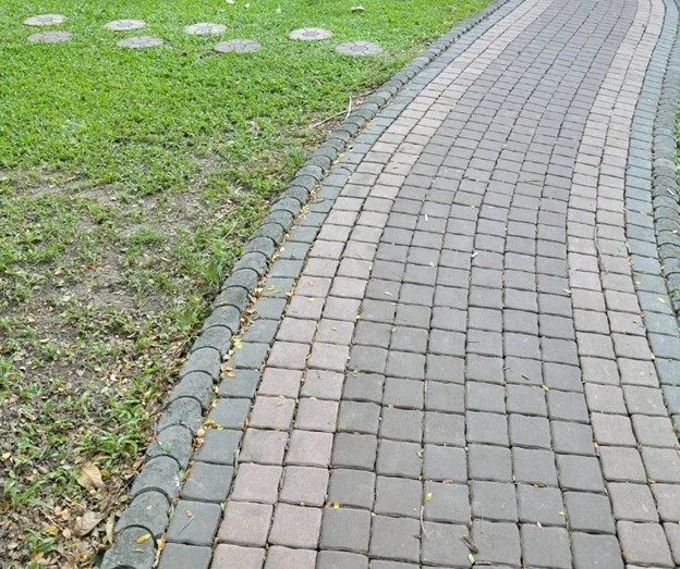 Paving walkways by Hawkins Landscaping featuring a curved brick paver walkway with decorative borders, creating an attractive and durable path through a residential landscape.