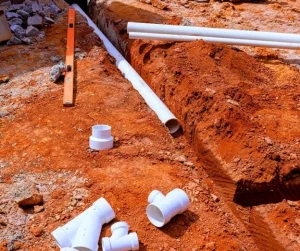Drainage experts by Hawkins Landscaping installing underground PVC drainage pipes in a properly graded trench to improve yard drainage and protect residential property from water damage.